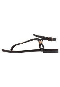Black flat sandals with braided straps and a gold accent. The design features a slender sole and an ankle buckle for adjustment.