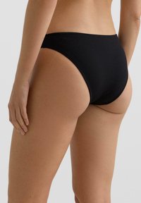Čierne pruhované spodné diely bikín s vysokým vystrihnutím nôh a minimálnym zakrytím. Mäkká textúra a bezšvové okraje zabezpečujú hladké priliehanie.