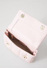 Różowa skórzana torebka o gładkiej fakturze, z dwoma złotymi zatrzaskami i wewnętrzną kieszenią. Otwarta górna część odsłania miękkie wykończenie.