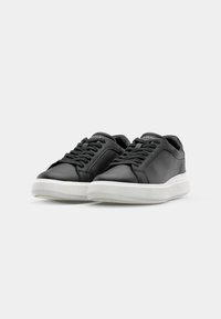 Schwarze Ledersneaker mit weißen Gummisohlen, featuring eine abgerundete Zehenpartie, Schnürdesign und minimalistische Stichdetails.