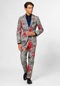 Gray suit with red splatter pattern, featuring a single-breasted jacket and matching trousers. Worn with a blue tie and black shirt.