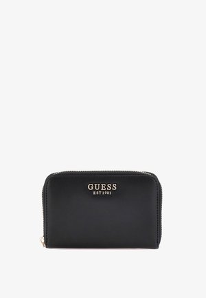 Zwarte leren portemonnee met gouden "GUESS EST 1981" logo. Ritssluiting, gladde textuur, rechthoekige vorm, geen patronen, minimale hardware.
