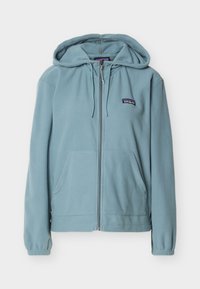 Ανοιχτό μπλε φλις φούτερ με φερμουάρ, εμπρός τσέπες, κουκούλα με κορδόνια, ελαστικές μανσέτες και μικρό λογότυπο Patagonia αριστερά στο στήθος.