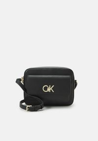 Borsa a tracolla in ecopelle nera con accessori dorati, forma rettangolare, tasca frontale con pattina e tracolla regolabile. Logo CK in evidenza.