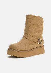 Stivaletto alla caviglia in suede color cammello con un motivo trapuntato, una fascia larga con una fibbia metallica e una suola in gomma spessa per un'altezza extra.