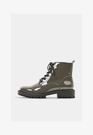 Botte à lacets grise foncée brillante, cheville, avec semelle épaisse à rainures marquées et languette à l'arrière, vue de profil sur un fond uni.