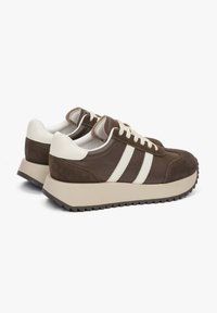 Brązowe skórzane i zamszowe sneakersy z białymi paskami, z zapięciem na sznurowadła i teksturowaną gumową podeszwą. Okrągły czubek i wyściełana obwódka.