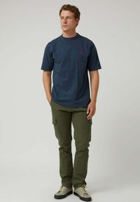 Camiseta de algodón azul marino con mangas cortas y cuello redondo; pantalones cargo verde oliva con bolsillos laterales; zapatillas grises con detalles negros.