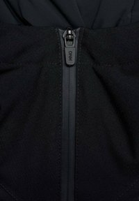 Tela negra con una textura suave que presenta una cremallera central, marcada con "MNG", y un diseño limpio y minimalista.