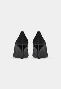 Black high-heeled shoes with a sleek, pointed toe, made from soft fabric. The stiletto heel is glossy, contrasting with the matte upper.