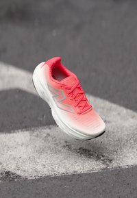 Baskets avec un dessus dégradé rose, semelle blanche, finition texturée et accents argentés réfléchissants. Les lacets sont serrés, avec un col rembourré.