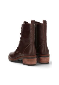 Botas de cuero marrón hasta el tobillo con punta redonda, cordones en la parte frontal y un tacón de madera en capas. Presentan costuras en contraste y una superficie texturizada.