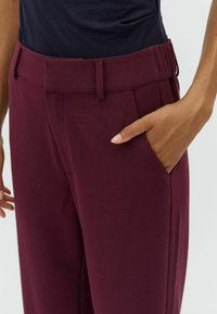 Bourgondische broek met rechte snit, gemaakt van textuurstof. Voorzien van zijzakken en een tailleband met lussen voor een riem.