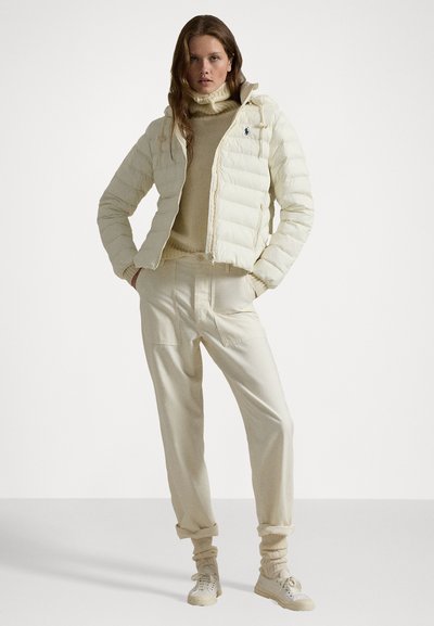 Ivory puffer jacket with horizontal quilted design, zip closure, drawstring hood, paired with cream sweater and matching pants. Sneakers included.