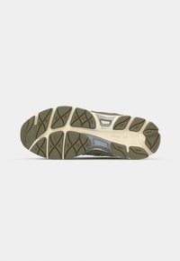 Semelle extérieure d'une chaussure de sport avec des motifs en caoutchouc olive et beige conçus pour l'adhérence et la durabilité.