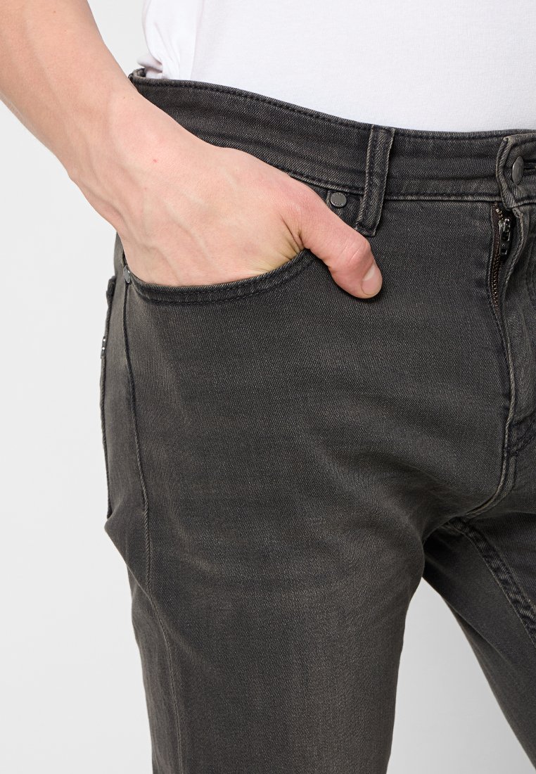 Jeans in denim nero con vestibilità slim, dotati di una chiusura con zip, tasca frontale e cuciture a contrasto lungo le cuciture. Texture morbida.