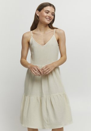 Vestido beige claro con escote en V, tirantes finos y falda en capas. Hecho de un tejido texturizado, con sutiles rayas horizontales.