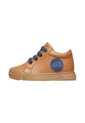 Sneaker in pelle tan con lacci blu, un'etichetta rotonda sul lato e suola in gomma testurizzata. Design a profilo basso con punta tondeggiante.