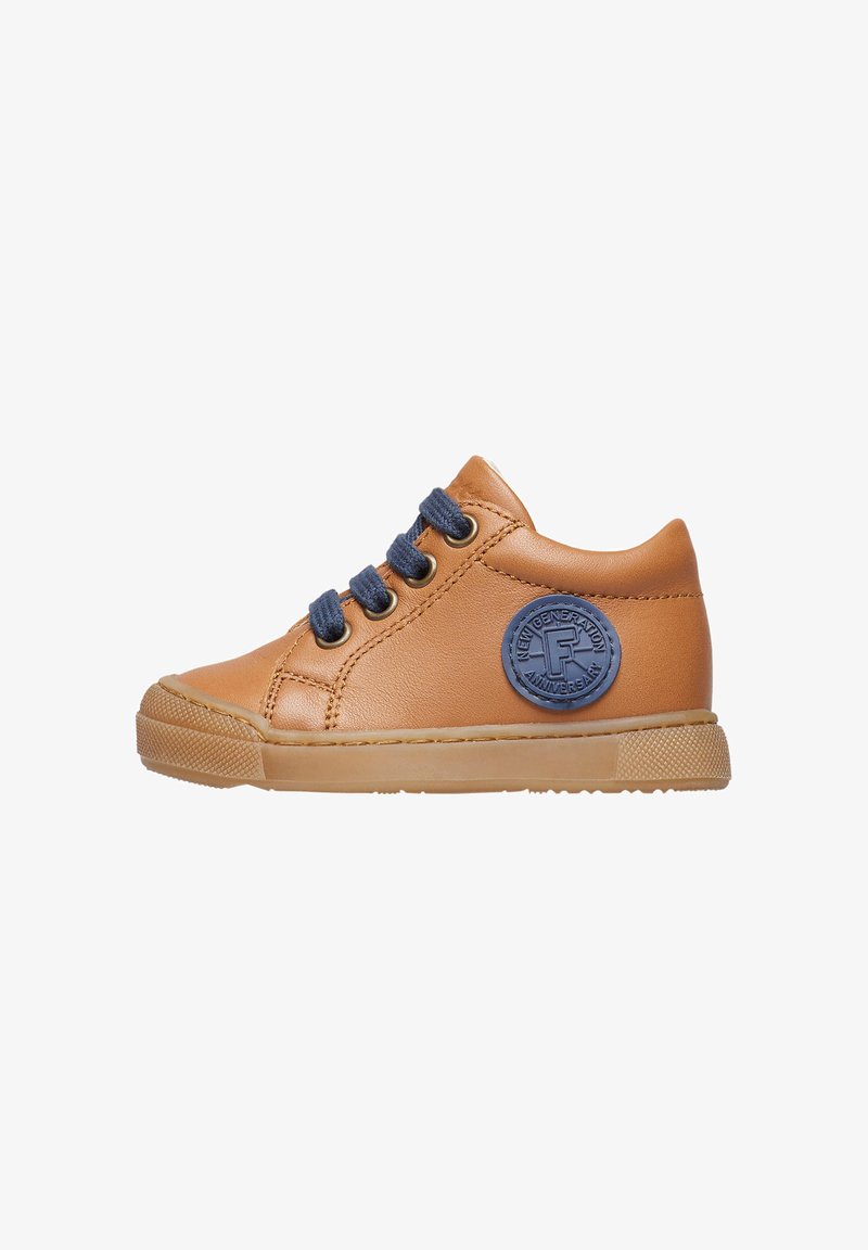 Hnědé kožené tenisky s modrými tkaničkami, kulatou logo nášivkou na boku a texturovanou gumovou podrážkou. Nízkoprofilový design s kulatou špičkou.