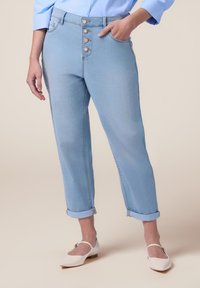 Jeans de mezclilla azul claro con cintura alta, puños enrollados y cierre frontal de cinco botones. Textura suave y diseño clásico.