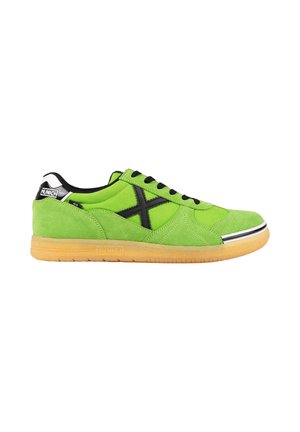 Zapatilla de ante verde brillante con cordones negros y logo, suela de goma y marca "Munich" en el talón y borde de la suela.