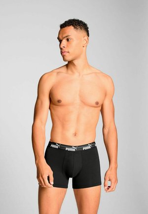 Black boxer briefs with a soft elastic waistband featuring white “PUMA” branding. Fabric appears smooth and stretchy, ensuring comfort.