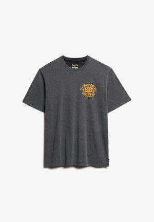 T-shirt en coton gris foncé avec un col rond. Présente un design graphique doré sur le côté gauche de la poitrine. Manches courtes et coupe décontractée.