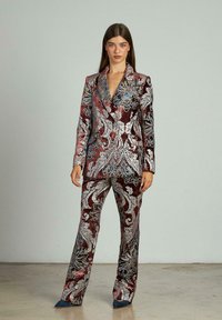 Traje de terciopelo en burdeos con intrincados patrones florales en plata, azul y blanco; cuenta con un blazer de solapa y pantalones ajustados.