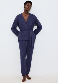 Navy ribben loungewear set met een wikkelstijl top met een riem en taps toelopende broeken. Gemaakt van zachte, textuurstof. Geschikt voor casual wear.