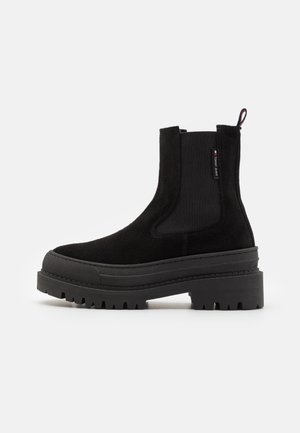 Svart mocka Chelsea-boots med tjock luggsole, elastiska sidopaneler, dragflik och liten Tommy Jeans-logotagg på sidan.