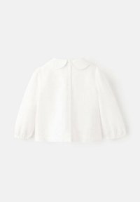 Bela bluza z dolgimi rokavi z zaobljenim ovratnikom in elastičnimi manšetami. Lahka tkanina z zapenjanjem na gumbe zadaj. Preprost, čist dizajn.