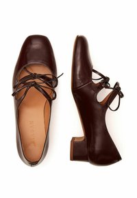 Scarpe in pelle marrone con punta quadrata, design con lacci, lati con intagli e tacco a blocco basso. Texture liscia con dettagli minimi.