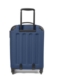 Hard-shell suitcase in navy blue, featuring ribbed texture, a retractable black handle, and four rotating wheels for mobility.