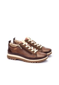 Zapatillas de cuero marrón con cordones crema, detalles texturizados en rosa y un zipper lateral. Cuentan con una suela acolchada y un patrón de tracción robusto.