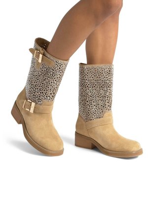 Tan-Farbenes Wildleder-Ankle-Boots mit einem Blockabsatz in mittlerer Höhe, featuring einer mit metallischen Nieten besetzten Oberseite, Riemen mit Schnallen und glatter Textur.