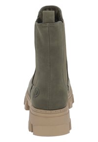 Bottine en suède verte avec une semelle beige épaisse, dotée d'une languette à l'arrière et de coutures le long des côtés.