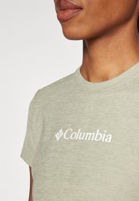 Lichtgroen, geribbeld T-shirt met korte mouwen, met een witte "Columbia"-logo op de borst en een zachte textuur.