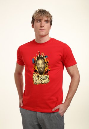 Ung mand iført en rød T-shirt med en farverig grafik af et ansigt og teksten "OLD DIRTY BASTARD" i stiliserede bogstaver.