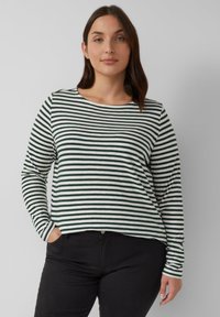 Langsleeve top met witte en donkergroene strepen. Ronde hals, relaxte pasvorm, zachte stof. Gecombineerd met zwarte jeans, handen in de zakken.