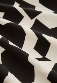 Svartvitt mönstrat tyg med geometriska former, slät textur och en djärv, kontrasterande design.
