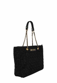 Schwarze gewebte Tragetasche mit strukturierter Oberfläche, goldfarbenen Kettenakzenten, Ledergriffen und einem Logoplate auf der Vorderseite.