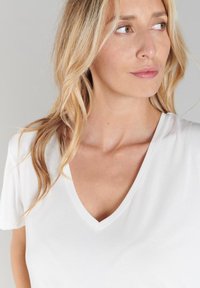 Witte korte mouwen V-hals T-shirt met een gladde textuur. De halslijn is iets puntig en benadrukt een ontspannen pasvorm.