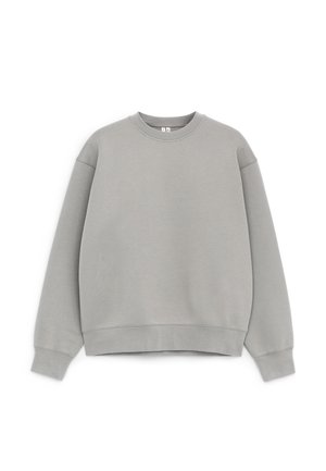 Šviesiai pilkas džemperis su apvalia iškirpte, ilgomis rankovėmis, ribinėmis rankogaliais ir apačia, išdėliotas plokščiai ant balto fono.