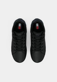 Černé tenisky s hladkým matným povrchem, kulatou špičkou, šněrováním a kontrastním námořnickým modrým akcentem na patě. Logo na jazyku.