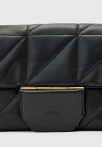 Czarna skórzana kopertówka z pikowanym wzorem, złotymi akcentami oraz prostokątną klapą z wytłoczonym logo na skórzanej naszywce.