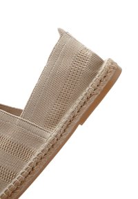 Scarpa slip-on in tessuto beige intrecciato con dettaglio in treccia lungo la suola, caratterizzata da una superficie testurizzata e un design leggero.