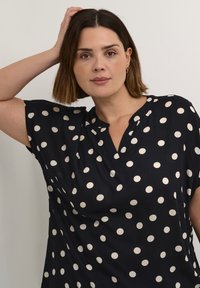 Maglietta blu navy a maniche corte, con scollatura a V e pois bianchi. Tessuto morbido con vestibilità comoda e design semplice.