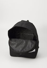Mochila negra con apertura con cremallera, presenta un exterior liso y duradero y un forro interior con estampado. Incluye un bolsillo interno con cremallera.