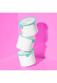 Three stacked white containers with turquoise lids and labels, on a pink background. Containers have a smooth, glossy finish.