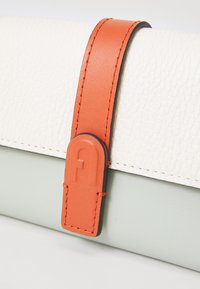 Tasje in drie kleuren met een gestructureerd witte leren oppervlak, een soepel lichtgroen leren gedeelte en een oranje hengsel met reliëf hardware detail.